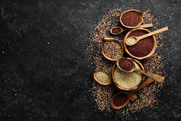 Semi di quinoa sul tavolo da cucina in legno vista dall'alto. Prodotto superfood sano e dietetico. Su uno sfondo di pietra nera.