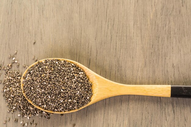 Semi sani di Chia in un cucchiaio di legno sul primo piano del tavolo.