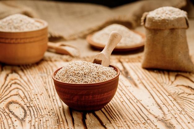 Semole d'orzo in ciotole e sacchi su uno sfondo di legno Foto di alta qualità