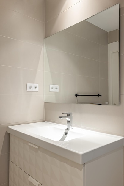 Semplice bagno vuoto e moderno con piastrelle beige lavabo e specchio