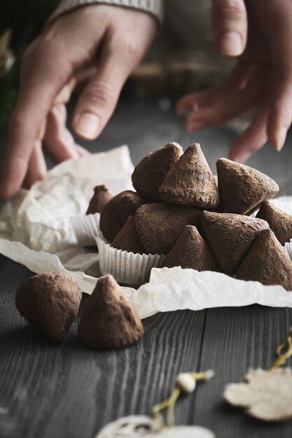 Semplice caramella al tartufo di Natale su un tavolo di legno con rami di piante.