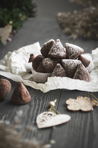 Semplice caramella al tartufo di Natale su un tavolo di legno con rami di piante.