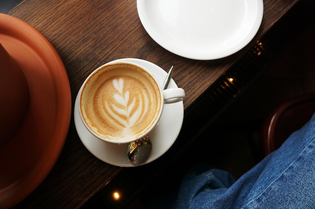 Semplice porzione di caffè cappuccino con arte floreale a forma di cuore su tavola di legno