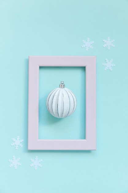 Semplicemente composizione minimale oggetti invernali ornamento palla in cornice rosa isolato su sfondo blu pastello alla moda. Natale Capodanno dicembre per il concetto di celebrazione. Vista dall'alto piatta