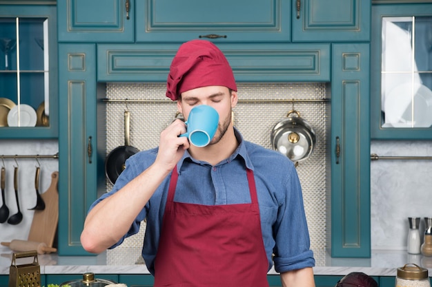 Semplicemente perfetto cuoco maschio in cucina indossare l'uniforme del personale uomo chef bere il tè L'uomo bello sta tenendo una tazza barista esperto e professionale lavora nel bar caffetteria o nel ristorante proprietario di una piccola impresa