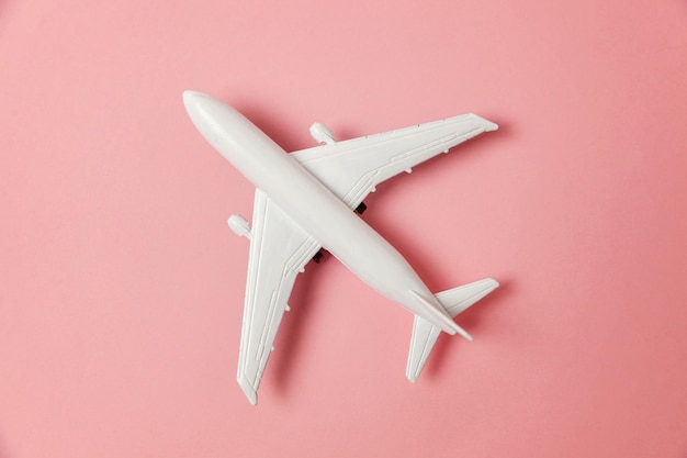 Semplicemente piatto design laici modello giocattolo in miniatura aereo su sfondo rosa pastello carta colorata alla moda viaggio in aereo vacanza estate fine settimana mare avventura viaggio biglietto tour concetto