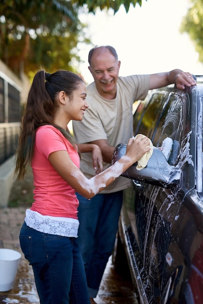 È sempre desiderosa di aiutare Inquadratura di un padre e una figlia che lavano un'auto insieme fuori