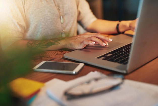 È sempre in cima a tutto Ripresa ritagliata di una giovane donna che usa il suo laptop mentre lavora fino a tardi nel suo ufficio