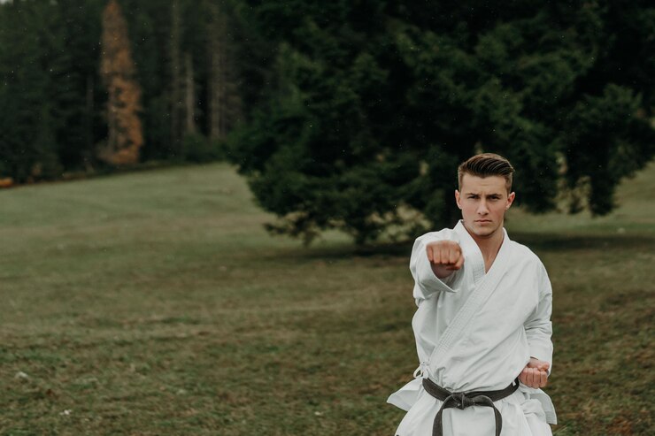 Seni bela diri karate seorang pria berkimono dengan sabuk hitam berlatih di ruang bebas gunung