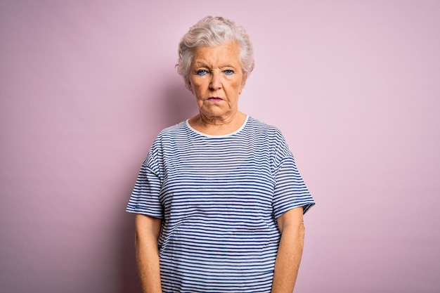 Senior bella donna dai capelli grigi che indossa una maglietta casual su sfondo rosa isolato con un'espressione seria sul viso Semplice e naturale guardando la fotocamera