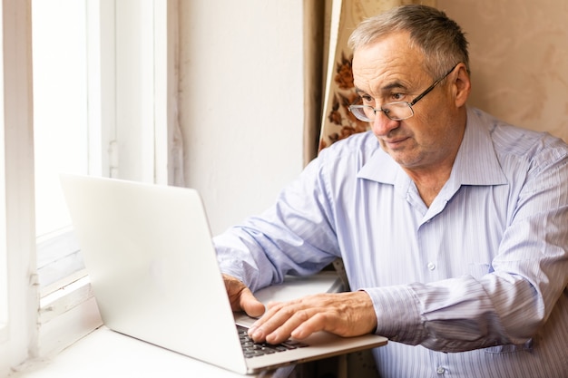 Senior che lavora su un laptop a casa