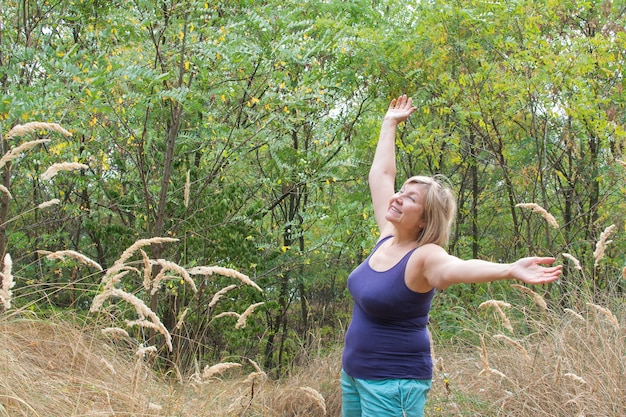 Senior donna braccia in alto e respirare all'aperto con la natura sullo sfondo del parco.