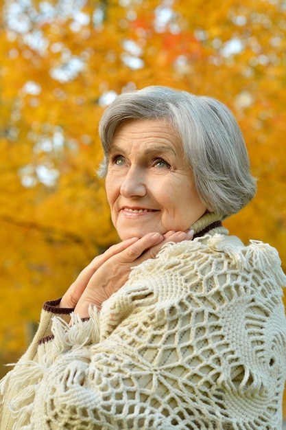 Senior donna che cammina nel parco in autunno