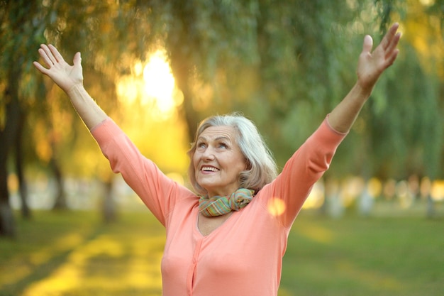 Senior donna che cammina nel parco in autunno