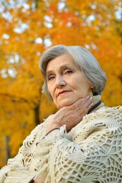 Senior donna che cammina nel parco in autunno