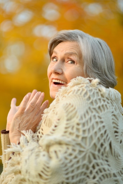 Senior donna che cammina nel parco in autunno