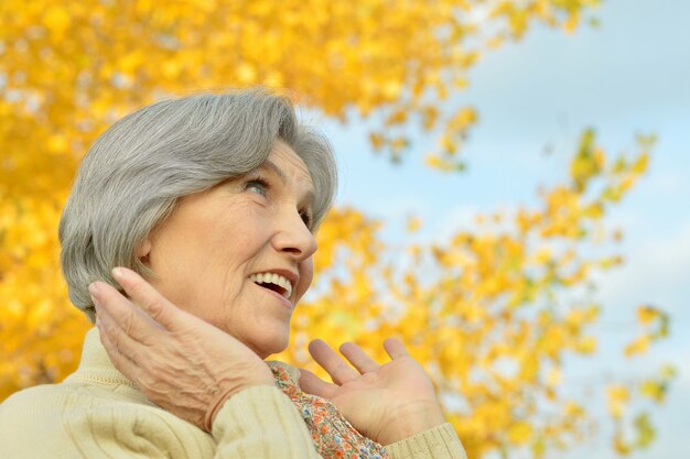 Senior donna che cammina nel parco in autunno