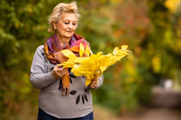 Senior donna che cammina nel parco in autunno