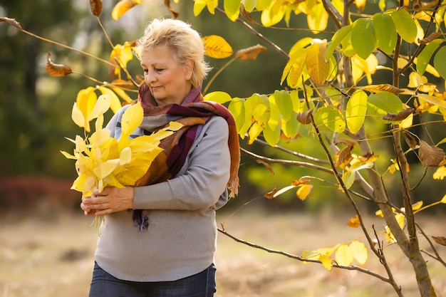 Senior donna che cammina nel parco in autunno