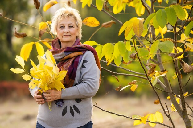 Senior donna che cammina nel parco in autunno