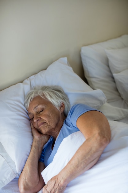 Senior donna che dorme in camera da letto a casa