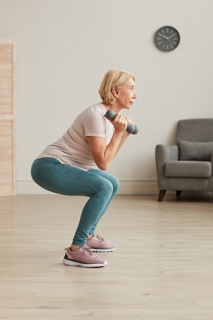 Senior donna che si esercita con manubri durante l'allenamento sportivo a casa