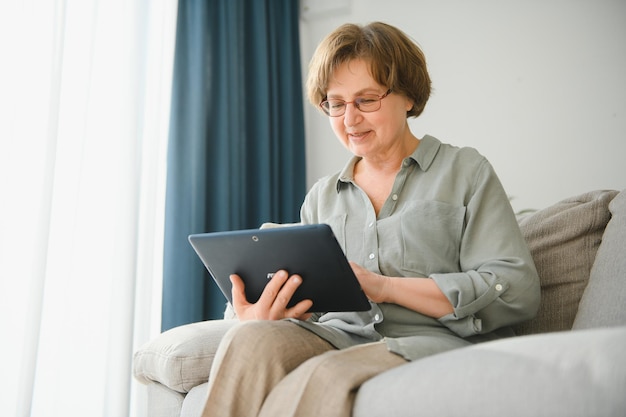 Senior donna con tavoletta digitale in soggiorno a casa