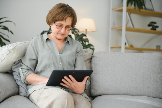 Senior donna con tavoletta digitale in soggiorno a casa