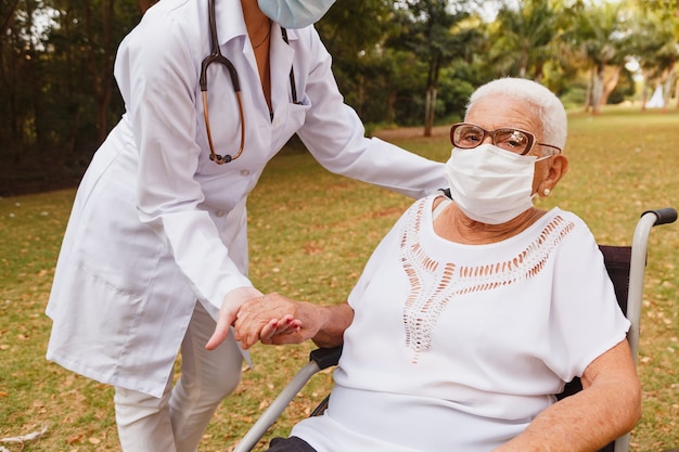 Senior donna disabile con badante nel giardino della casa di cura