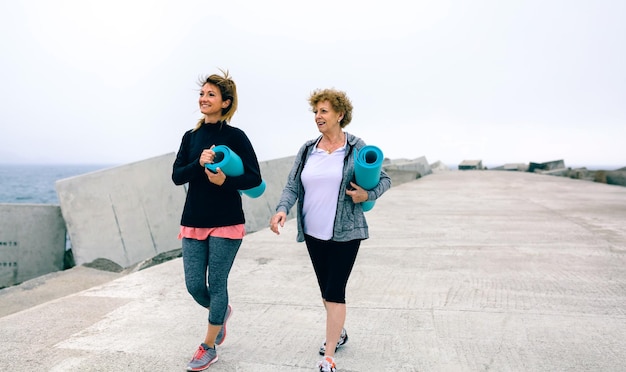 Senior donna e giovane donna che camminano all'aperto dal molo del mare