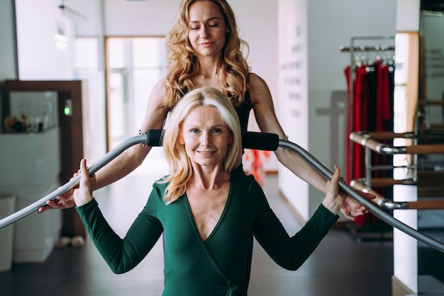 Senior donna facendo riabilitazione fisica e pilates con il suo allenatore nel centro sportivo