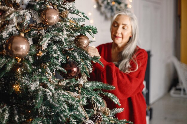 Senior donna in piedi e decorare l'albero di Natale