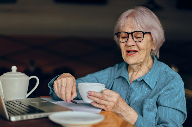 Senior donna in un caffè una tazza di bevanda portatile donna in pensione in chat inalterato