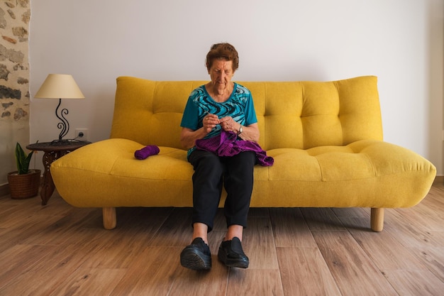 Senior donna seduta su un divano a maglia