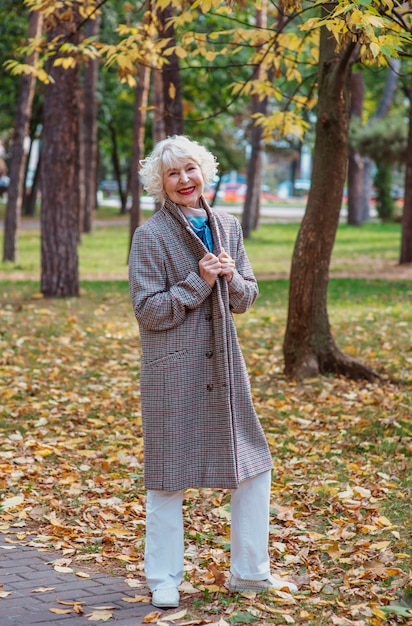 Senior elegante elegante donna alla moda in cappotto all'aperto in autunno park vecchiaia stagioni cadono