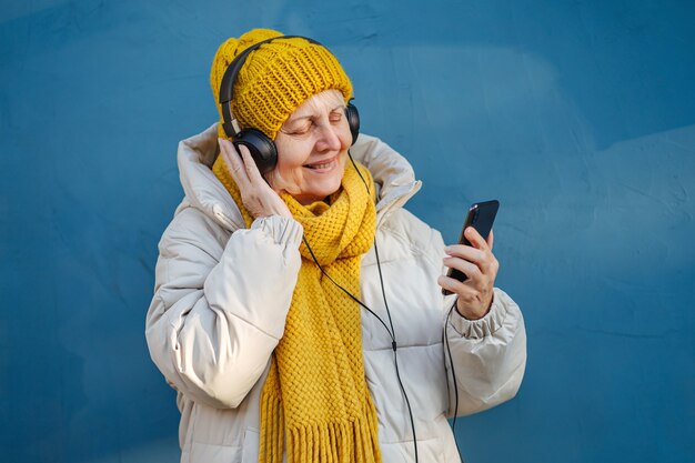 Senior femminile che ascolta la musica e utilizza lo smartphone.