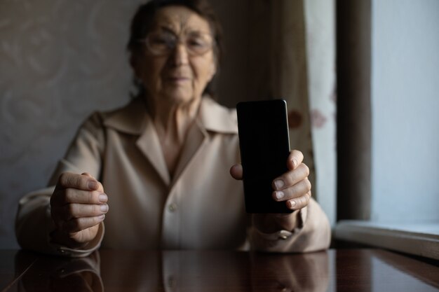 Senior femminile con il suo smartphone, una donna molto anziana mostra il suo telefono