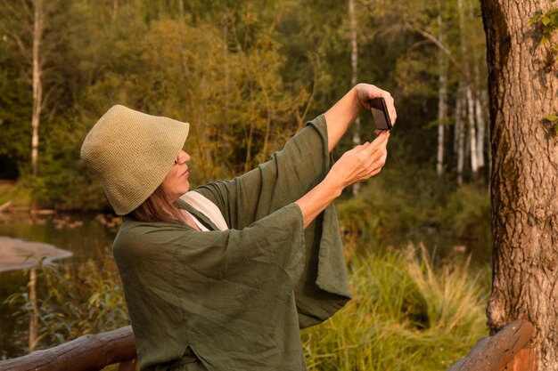 Senior lady prendendo ritratto selfie per telefono a piedi nel parco in autunno