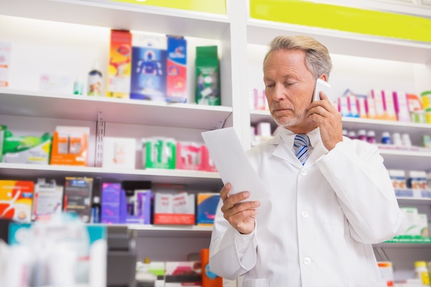 Senior sorridente telefonando durante la lettura di prescrizione