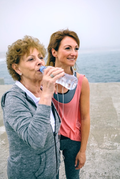 Senior sportiva acqua potabile con allenatore femminile dal molo del mare