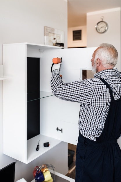 Senior tuttofare che lavora in cucina. Ristrutturazione.