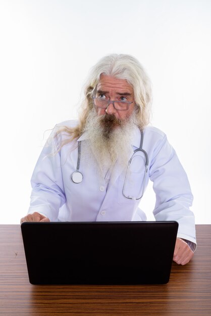 Senior uomo barbuto medico indossando occhiali durante l'utilizzo di laptop