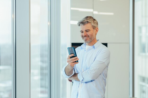 Senior uomo d'affari capo in ufficio moderno ritratto di imprenditore utilizzando il telefono sorridente e gioendo