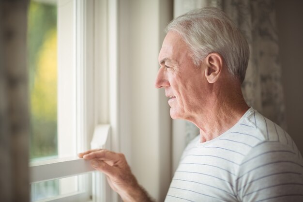 Senior uomo in piedi dalla finestra