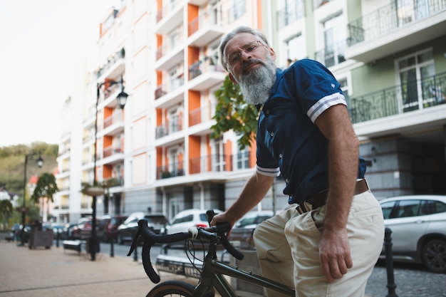 Senior uomo seduto sulla sua bicicletta sorridendo alla telecamera