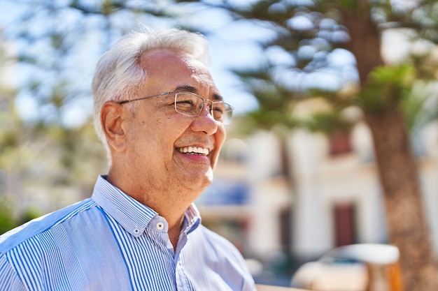 Senior uomo sorridente in piedi fiducioso al parco