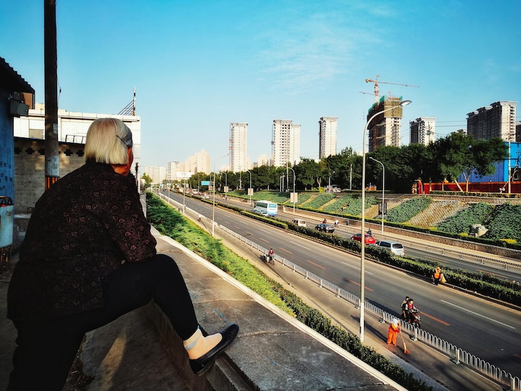 Photo senior woman looking at buildings at road from terrace