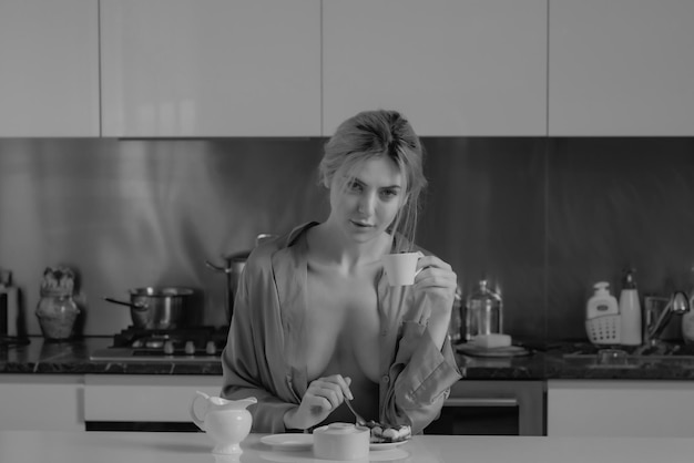 Seno nudo donna sexy bere caffè vicino al tavolo in cucina a casa casalinga in cucina al mo