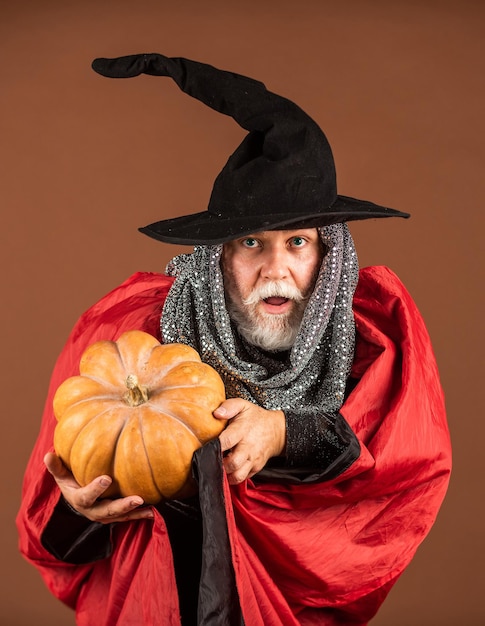 Sensazione di paura. 31 ottobre. uomo gotico in costume di Halloween. uomo anziano tenere la zucca. vecchio con cappello e mantello magici. Jack-o-lantern. Orrore di fantasia Halloween. Decorazione di Halloween e concetto spaventoso.