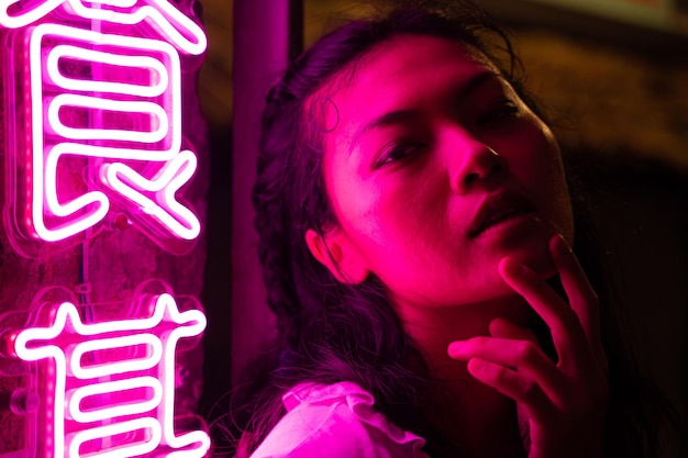 Sensuale donna asiatica illuminata da luci al neon nella notte